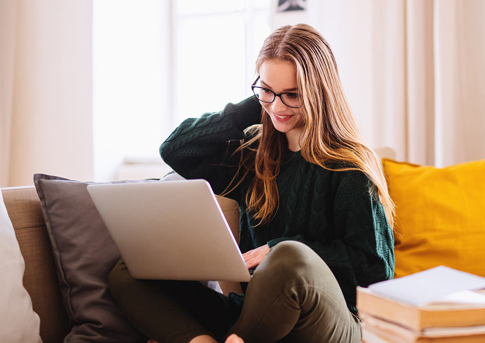 Girl using laptop on couch at home.