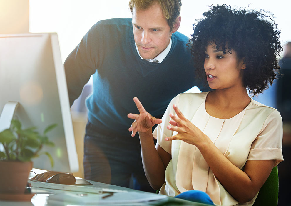 Male and female coworkers looking at a computer.