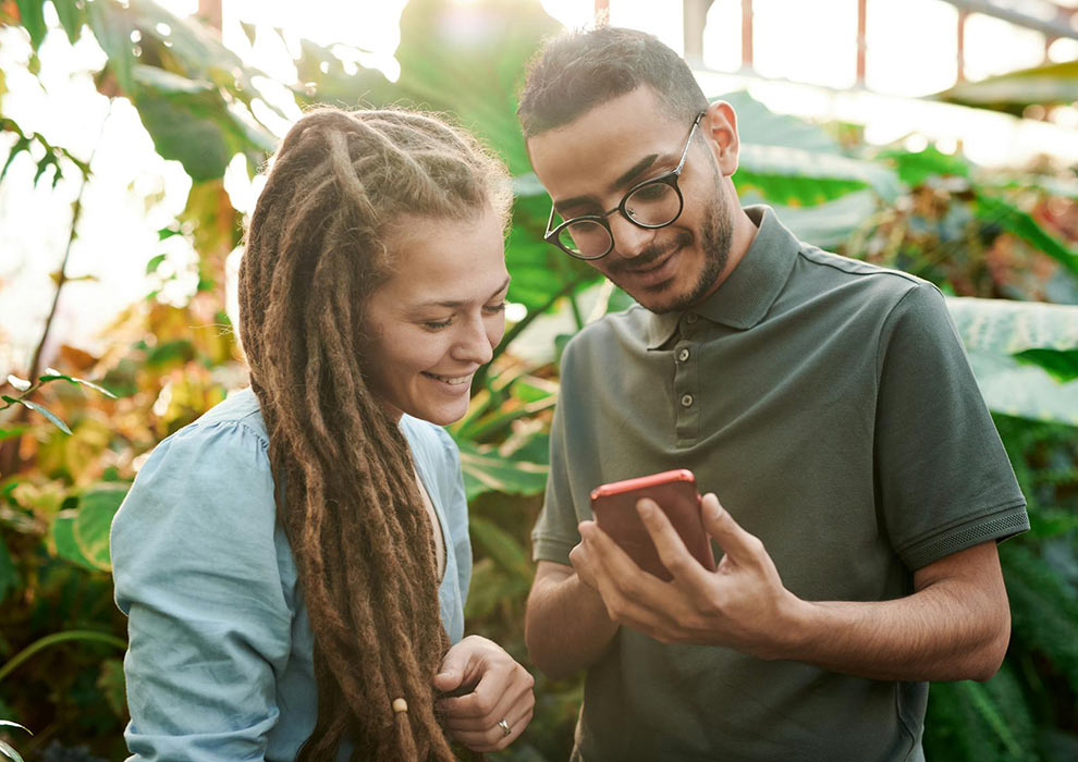 Couple looking at phone surrounded by plants.